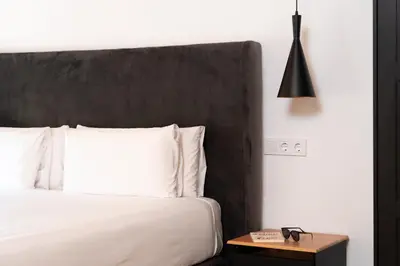 a bedroom with a white bed and a black headboard at Dúplex Deluxe Apartment in Badalona