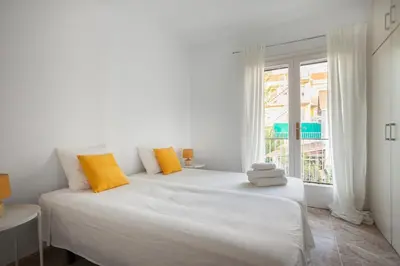 a white bedroom with a large bed with yellow pillows at Marina beach Castelldefels in Castelldefels