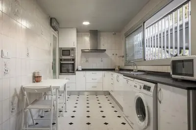 a kitchen with a washer and a sink and a table at Marina beach Castelldefels in Castelldefels