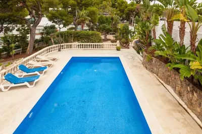 a swimming pool with blue water and two lounge chairs at Villa Drago in Castelldefels