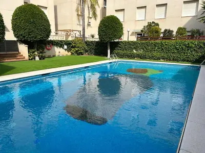 a blue swimming pool in front of a building at Apartment Rivel in Cubelles