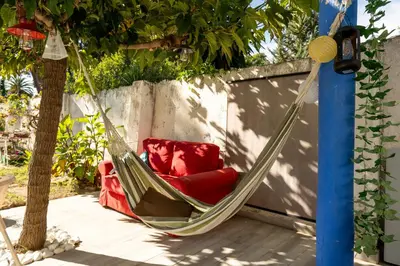 a hammock with a red chair on a patio at Atenea Room by the Beach - Claire Homes in Castelldefels
