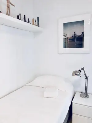 a white bedroom with a bed and a lamp at Pineda 38 in Gavà