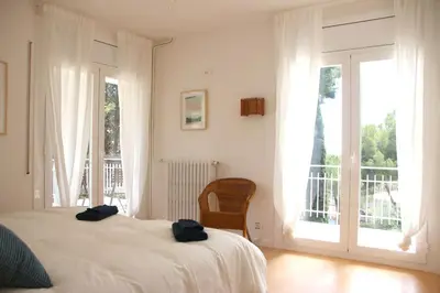 a bedroom with a bed and a balcony with windows at VILLA Mar y Montaña in Castelldefels