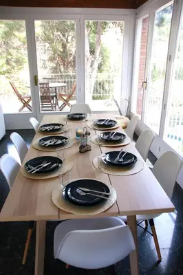 a wooden table with chairs and plates on it at VILLA Mar y Montaña in Castelldefels