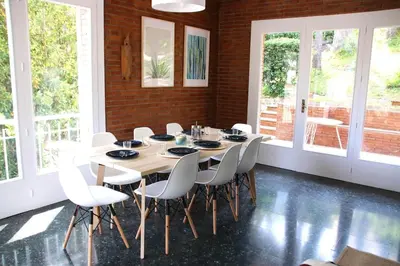 a dining room with a table and white chairs at VILLA Mar y Montaña in Castelldefels