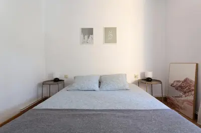a white bedroom with a bed with two side tables at Apartamento en castelldefels in Castelldefels