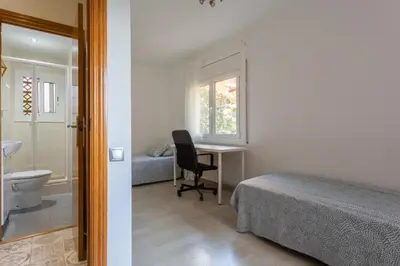 a bedroom with a bed and a desk and a bathroom at Apartamento en castelldefels in Castelldefels