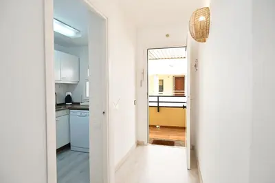 a kitchen with white cabinets and a door leading into a room at Apartamento con piscina en Sant Pol de Mar in San Pol de Mar