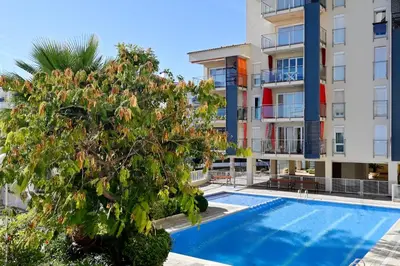 an apartment building with a pool and a tree at Apartamento con piscina en Sant Pol de Mar in San Pol de Mar