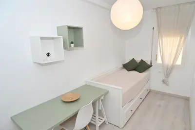 a white room with a bed and a desk at Apartamento con piscina en Sant Pol de Mar in San Pol de Mar