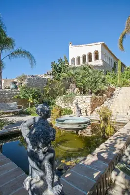 a statue of a girl sitting in a pond in front of a building at Alcazar Del Garraf in Olivella