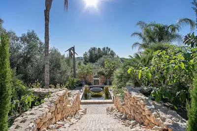 a garden with a fountain and a stone wall at Alcazar Del Garraf in Olivella