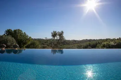 a blue swimming pool with the sun in the background at Alcazar Del Garraf in Olivella