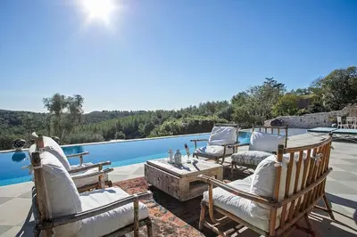 a group of chairs sitting on a patio next to a pool at Alcazar Del Garraf in Olivella