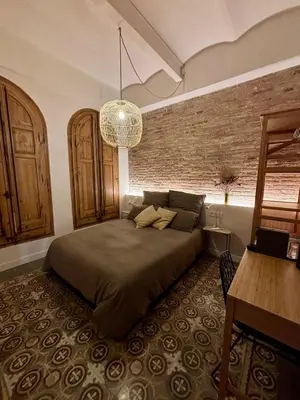 a bedroom with a bed and a brick wall at Cozy Suite in a historic house near the sea in Vilanova i la Geltrú