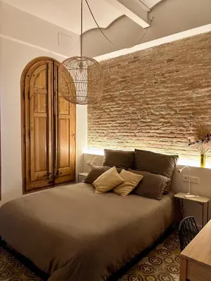 a bedroom with a large bed with a brick wall at Cozy Suite in a historic house near the sea in Vilanova i la Geltrú
