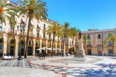 a courtyard with palm trees in front of a building at Cozy Suite in a historic house near the sea in Vilanova i la Geltrú