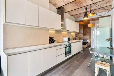 a kitchen with white cabinets and a table at Gràcia Monthly 1BR Sunny Private Terrace in Barcelona