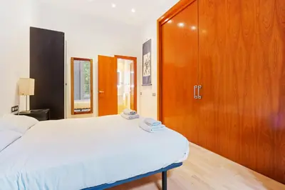a bedroom with a bed and a wooden cabinet at Quiet, vibrant 2 bedroom in pedestrian Eixample in Barcelona
