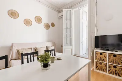 a white living room with a table and a tv at 5BR for 7 Elevator Walk to Sant Antoni in Barcelona