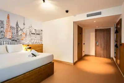 a bedroom with a white bed and a wall with a picture at easyHotel Barcelona La Sagrera in Barcelona