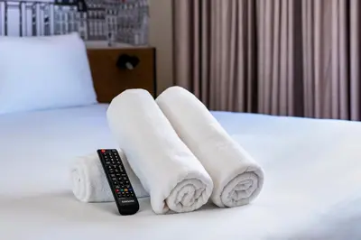 a pile of towels and a remote control on a bed at easyHotel Barcelona La Sagrera in Barcelona