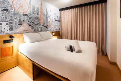 a bedroom with a large white bed with a clock on the wall at easyHotel Barcelona La Sagrera in Barcelona