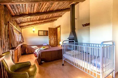 a bedroom with a crib and a bed in a room at Casa Rural CAN PANXA in Sant Pere de Vilamajor