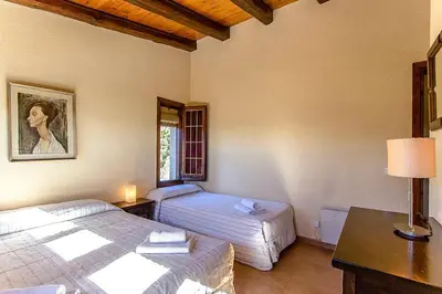 a bedroom with two beds and a table with a lamp at Casa Rural CAN PANXA in Sant Pere de Vilamajor