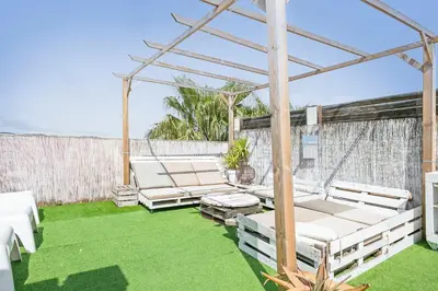 a patio with white chairs and a pergola at Apartamento Cubelles Molí Baix in Cubelles