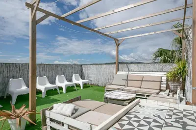 a patio with white furniture and chairs on the grass at Apartamento Cubelles Molí Baix in Cubelles