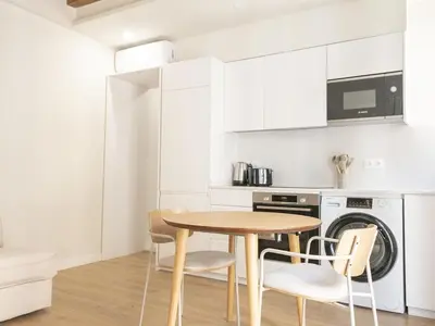 a small kitchen with a wooden table and chairs at Winahost La Barceloneta in Barcelona