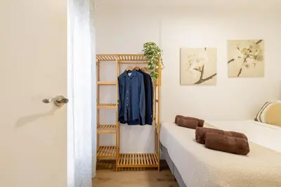 a room with two beds and a clothes rack at Apartamento 3 hab Fira de Bcn a 20 minutos de Bcn Centro in Hospitalet de Llobregat