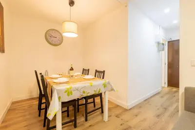 a dining room with a table with chairs and a clock at Apartamento 3 hab Fira de Bcn a 20 minutos de Bcn Centro in Hospitalet de Llobregat