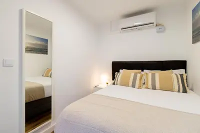 a white bedroom with a bed and a mirror at Apartamento 3 hab Fira de Bcn a 20 minutos de Bcn Centro in Hospitalet de Llobregat