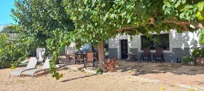 a building with chairs and a table and a tree at A Country and Vineyard Retreat in San Martín Sarroca