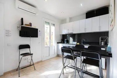 a kitchen with black counter chairs and white cabinets at Nice apartment in Gracia - Torrent de l'Olla in Barcelona