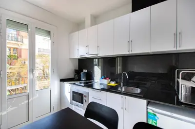 a kitchen with white cabinets and black counter tops at Nice apartment in Gracia - Torrent de l'Olla in Barcelona