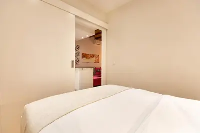 a bedroom with a white bed and a refrigerator at Blasco de Garay: acogedor apartamento en el corazón de Poble-sec in Barcelona
