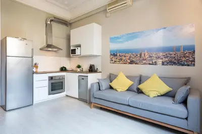 a living room with a couch and a kitchen at Suites4days Ali bei Apartment in Barcelona