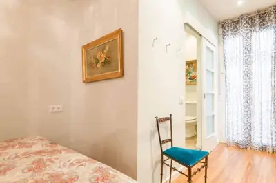 a room with a bed and a chair and a window at Explore City Center from an Elegant Urban Retreat in Barcelona