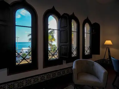 a room with four windows and a chair and the ocean at Las Ventanas Sea Front by Hello Homes Sitges in Sitges