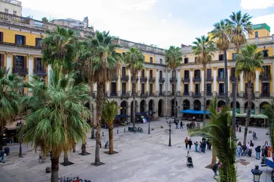 a city square with palm trees in front of a building at Hostal Ambos Mundos in Barcelona