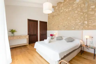 a bedroom with a white bed and a stone wall at Masía La Torre Historia Encanto y Naturaleza a Solo 10 Minutos de Sitges Gran comodidad, Vista a los Viñedos en un pueblo autentico in Viladellops