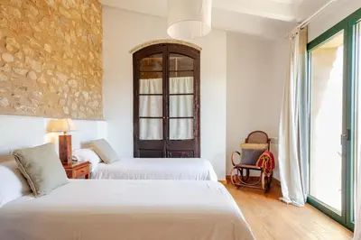 a hotel room with two beds and a chair at Masía La Torre Historia Encanto y Naturaleza a Solo 10 Minutos de Sitges Gran comodidad, Vista a los Viñedos en un pueblo autentico in Viladellops