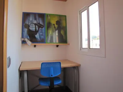 a desk with a blue chair and a window at FlexCo City - Barcelona Flats in Barcelona