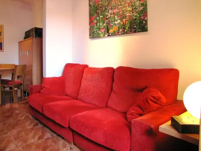 a red couch in a living room with a painting at FlexCo City - Barcelona Flats in Barcelona