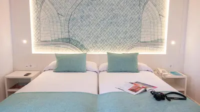 a white bed with two pillows and a book on it at Golden Taurus Aquapark Resort in Pineda de Mar