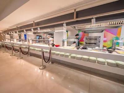 a kitchen with people preparing food in a restaurant at Golden Taurus Aquapark Resort in Pineda de Mar